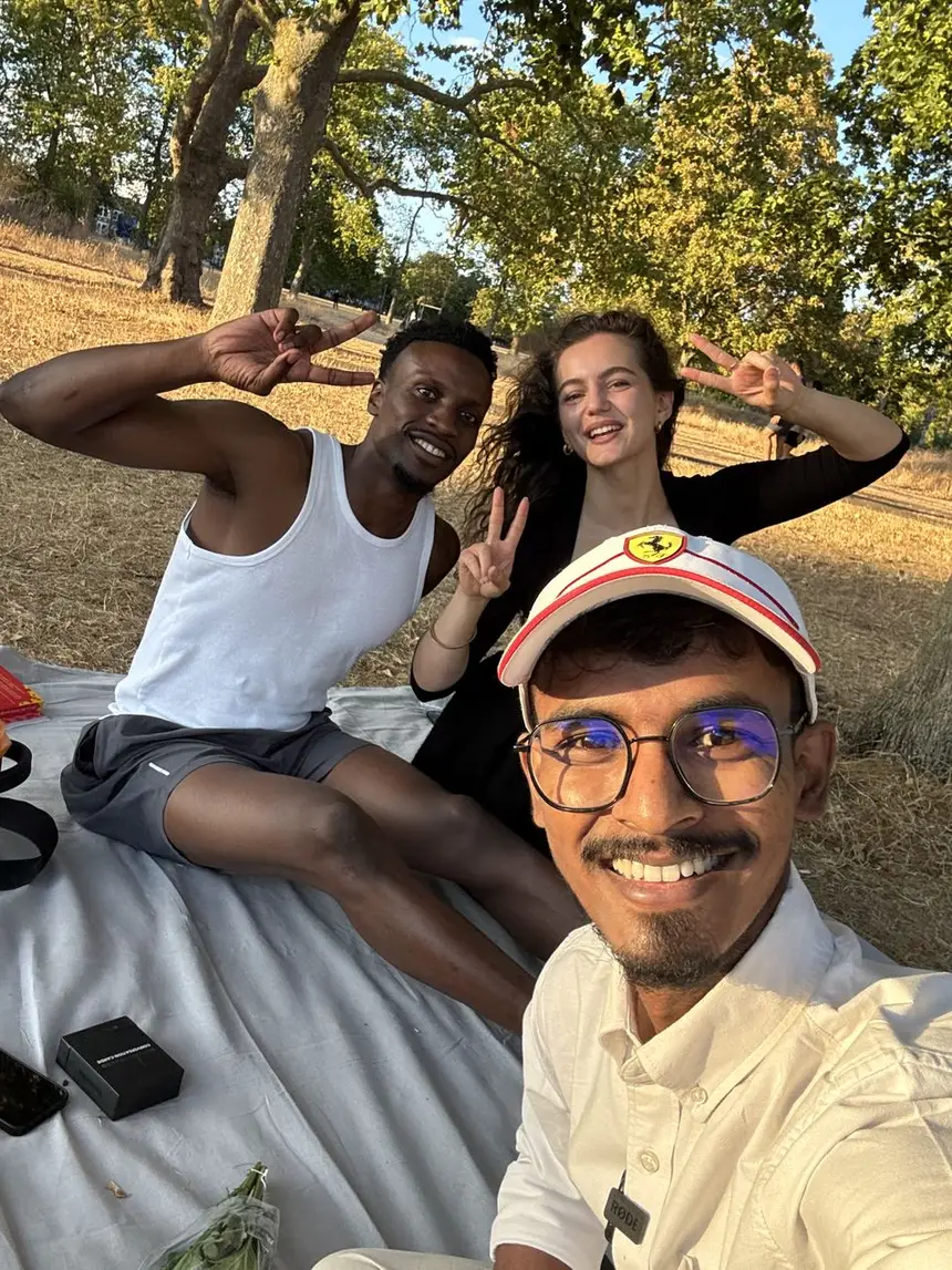 Vasu with three friends sitting on the grass in a park.