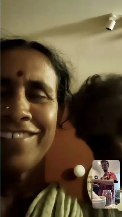 A video call with Vasu's mother, her face filling the screen and Vasu in the small window.