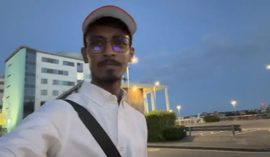 Vasu outside a university campus at dusk.