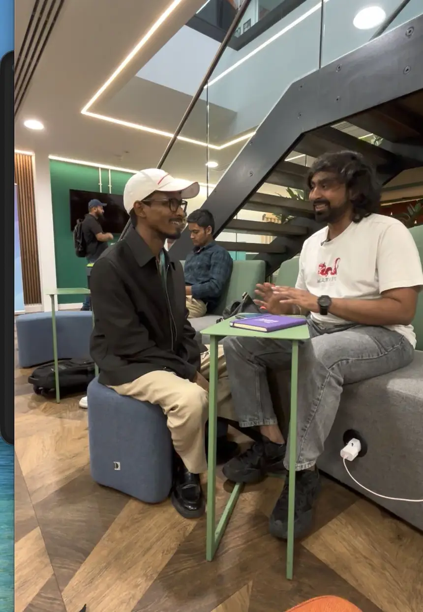 Vasu sitting and talking with a student inside a university building.